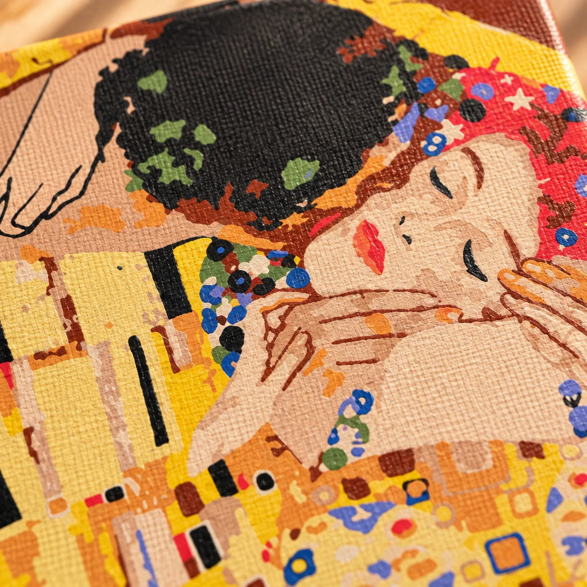 Close-up of The Kiss paint by numbers canvas showing painted texture and detailed warm colours